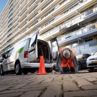 Macero voert rioolreiniging uit naast een bedrijfsbus